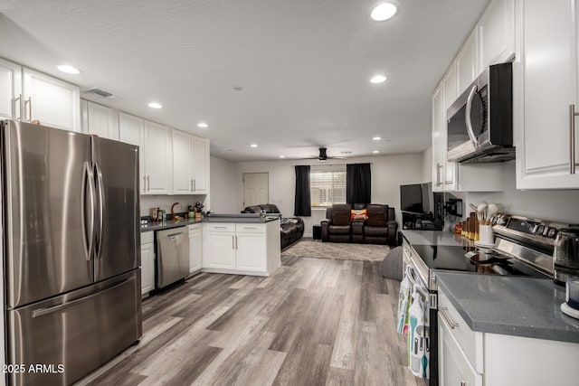 11132 W Indiana Ave, Youngtown, AZ 85363 - kitchen with stainless steel appliances, dark countertops, open floor plan, white cabinets, and recessed lighting