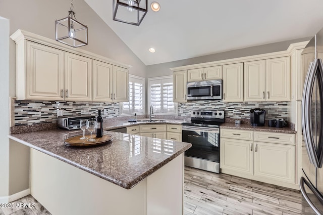 kitchen with appliances with stainless steel finishes, cream cabinets, and kitchen peninsula