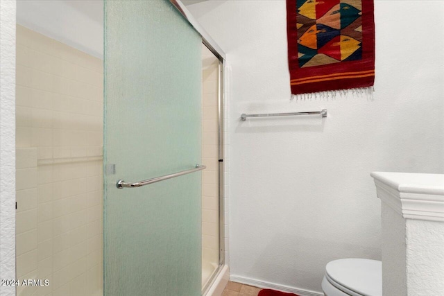 bathroom featuring toilet and a shower with shower door