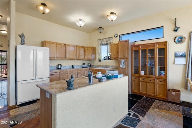 kitchen with light countertops, freestanding refrigerator, and a kitchen island