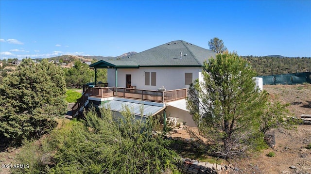 rear view of property featuring stucco siding and a deck with mountain view
