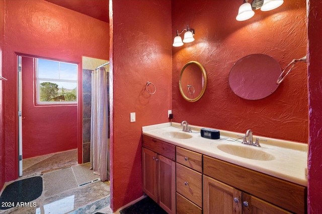 bathroom featuring double vanity, walk in shower, and a sink