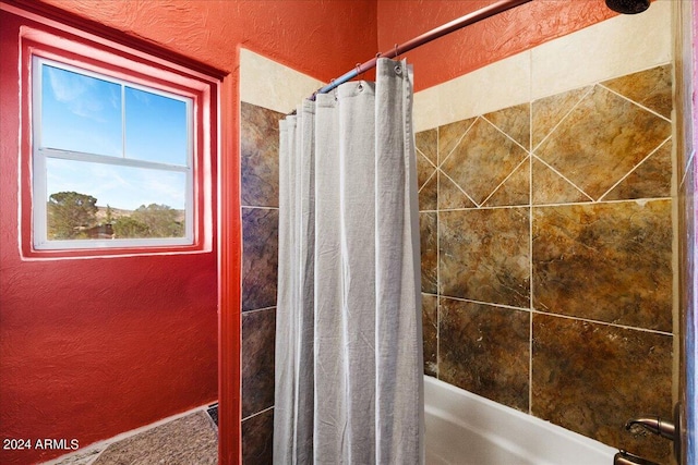 bathroom featuring shower / bathtub combination with curtain and a textured wall