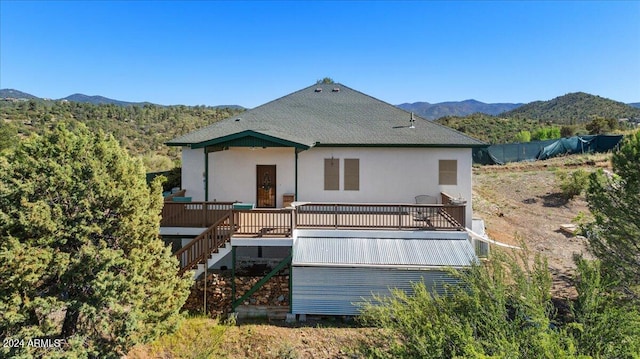rear view of property with stairs, a shingled roof, stucco siding, and a deck with mountain view