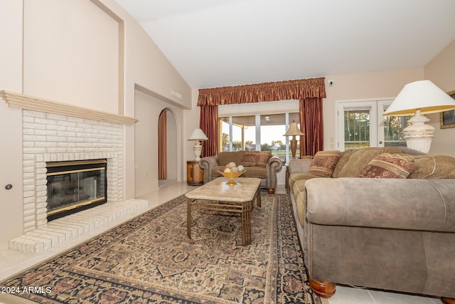 living room featuring light tile patterned floors, high vaulted ceiling, and a brick fireplace