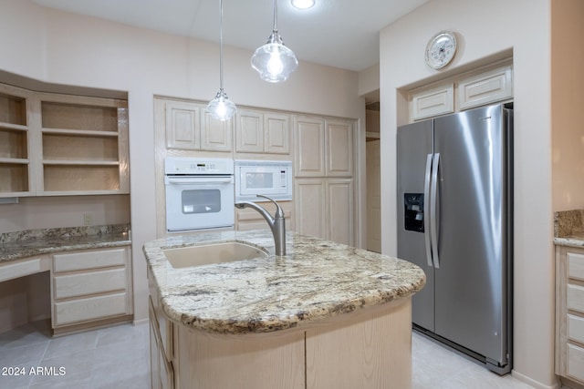 kitchen featuring light stone countertops, white appliances, a kitchen island with sink, and sink