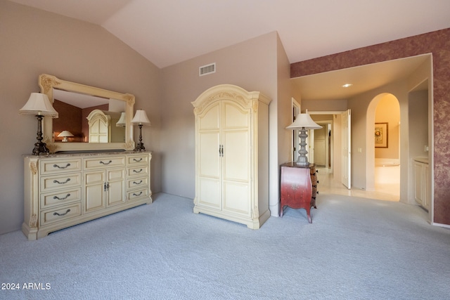 unfurnished bedroom with ensuite bathroom, lofted ceiling, and light colored carpet