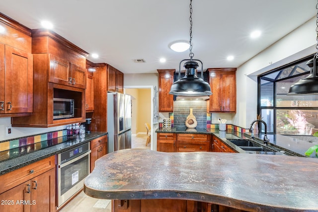 kitchen featuring pendant lighting, sink, dark stone countertops, backsplash, and stainless steel appliances