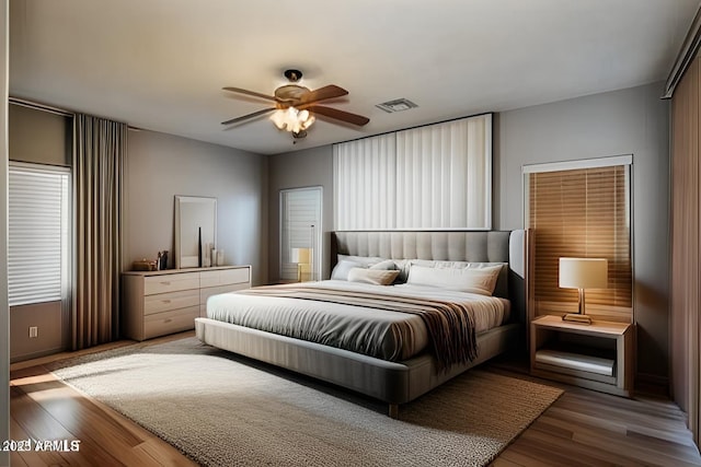 bedroom with a ceiling fan, visible vents, and wood finished floors