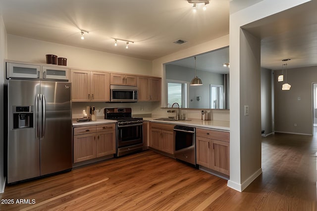 kitchen with stainless steel appliances, a sink, visible vents, light countertops, and dark wood finished floors