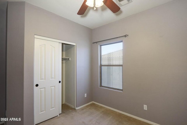 unfurnished bedroom featuring ceiling fan, light carpet, visible vents, baseboards, and a closet
