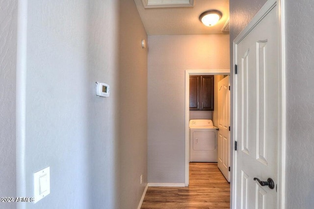 corridor featuring washer / dryer, light wood-style floors, and baseboards