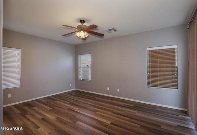 spare room featuring baseboards, visible vents, and dark wood-style flooring