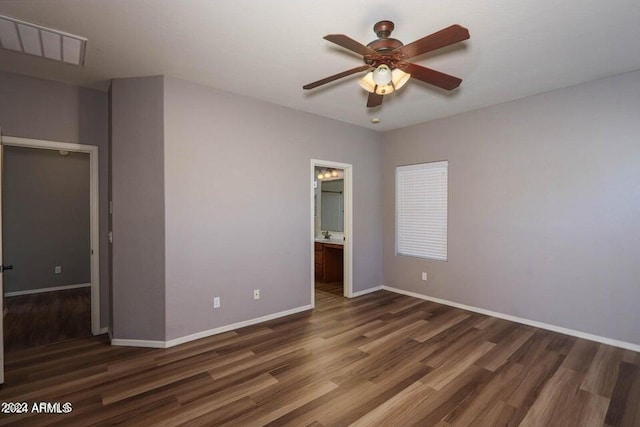 unfurnished bedroom featuring baseboards, visible vents, ceiling fan, wood finished floors, and ensuite bathroom