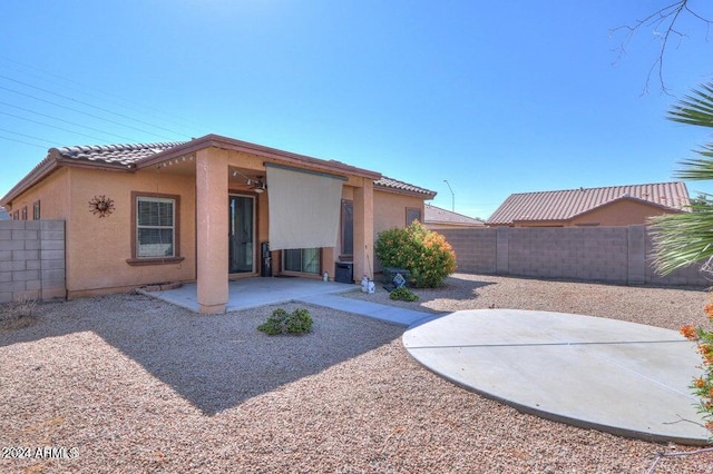back of house with a tiled roof, a patio area, a fenced backyard, and stucco siding