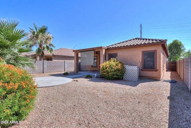 view of front of property featuring a tile roof, a patio, a fenced backyard, and stucco siding