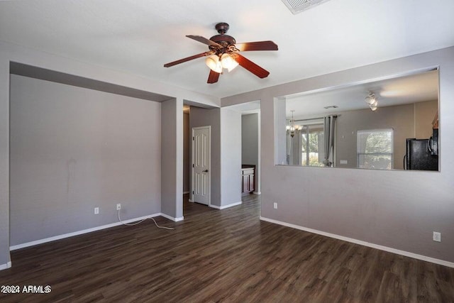 unfurnished room featuring ceiling fan with notable chandelier, wood finished floors, visible vents, and baseboards
