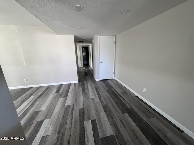 unfurnished room featuring a textured ceiling and dark hardwood / wood-style floors