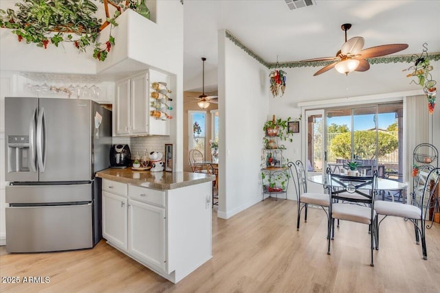 kitchen featuring stainless steel fridge, ceiling fan, tasteful backsplash, light wood-type flooring, and white cabinets