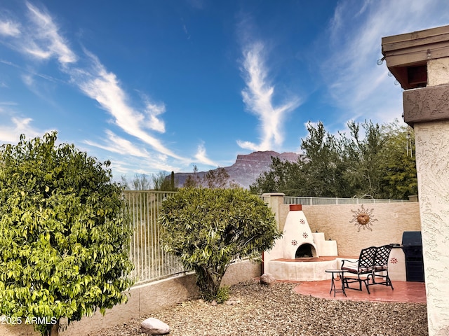 view of yard featuring exterior fireplace, a mountain view, and a patio