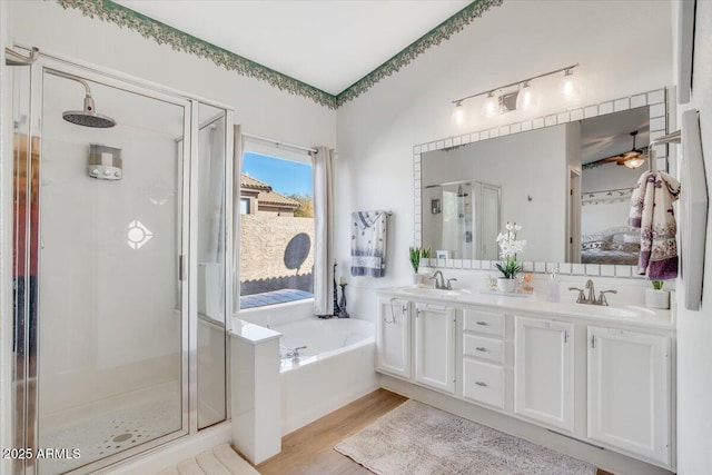 bathroom featuring hardwood / wood-style flooring, vanity, ceiling fan, and plus walk in shower