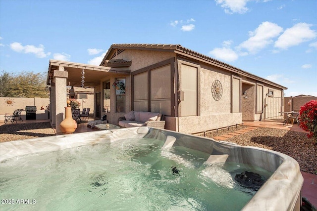 back of property featuring a hot tub and a patio