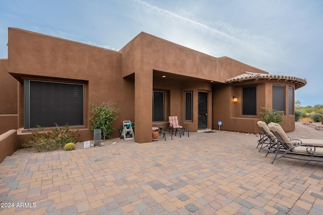 back of house with stucco siding and a patio