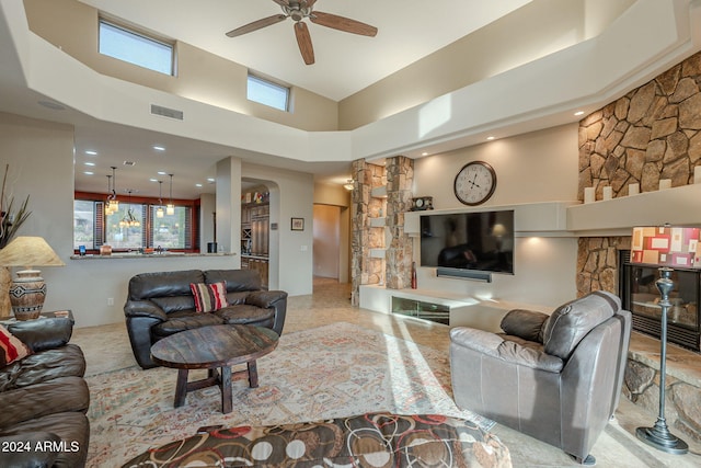 living area with arched walkways, a fireplace, visible vents, a high ceiling, and a ceiling fan