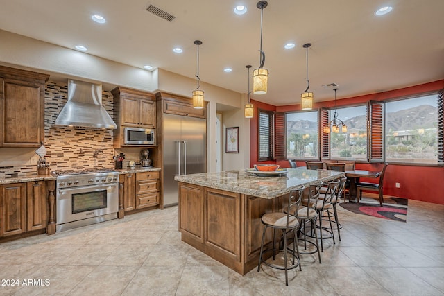 kitchen featuring brown cabinets, visible vents, wall chimney exhaust hood, and built in appliances