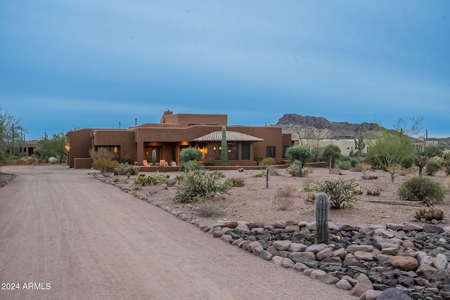 view of front of home with dirt driveway, a chimney, and a mountain view