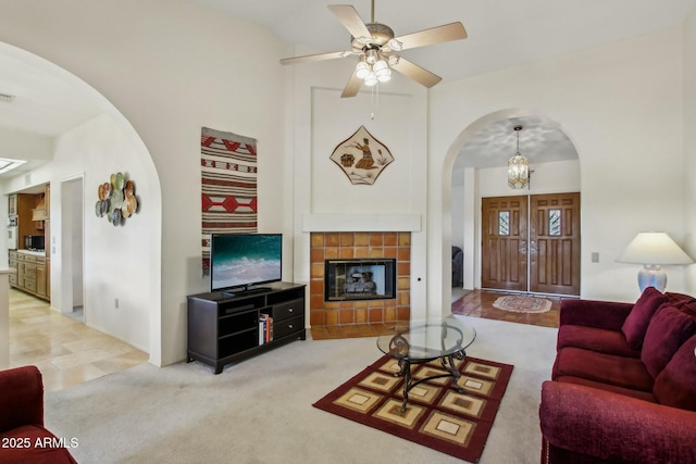 living room featuring a tiled fireplace, carpet flooring, and ceiling fan