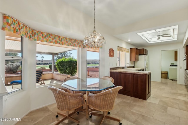 dining space with washer / dryer, sink, and an inviting chandelier