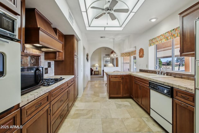 kitchen with premium range hood, sink, pendant lighting, white appliances, and decorative backsplash