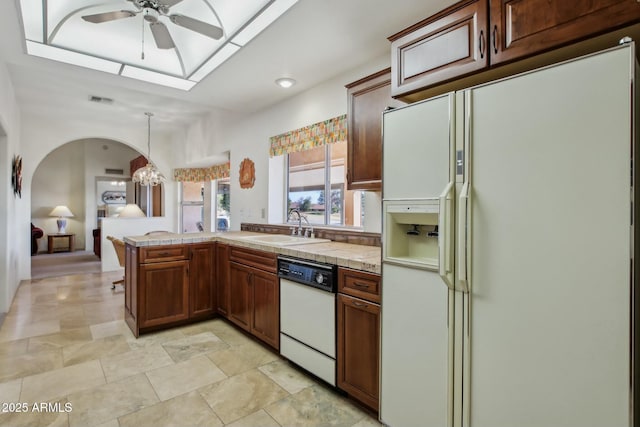 kitchen with sink, hanging light fixtures, kitchen peninsula, white appliances, and ceiling fan with notable chandelier