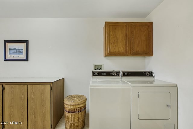 clothes washing area featuring cabinets and washer and clothes dryer