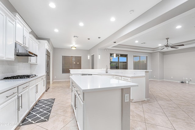 kitchen with stainless steel appliances, light tile patterned flooring, a sink, an island with sink, and under cabinet range hood