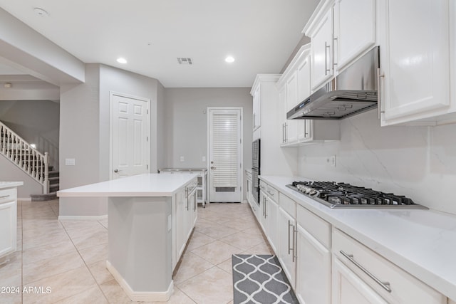 kitchen featuring light tile patterned floors, white cabinetry, a kitchen island, and stainless steel appliances