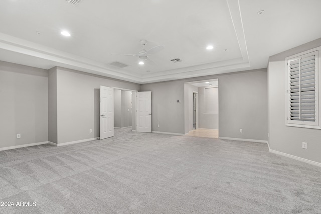 carpeted empty room with a tray ceiling and ceiling fan