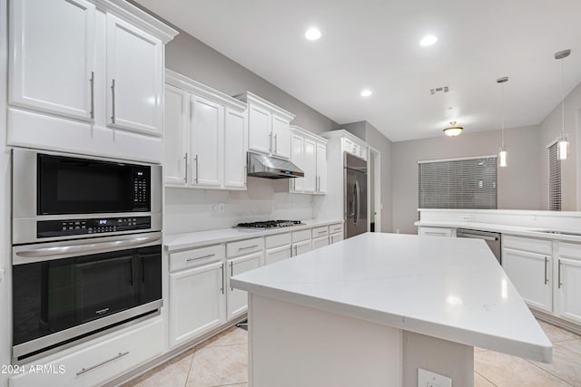 kitchen with a center island, visible vents, light tile patterned flooring, built in appliances, and under cabinet range hood