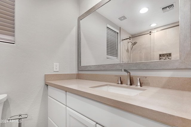 bathroom with tiled shower, vanity, and toilet