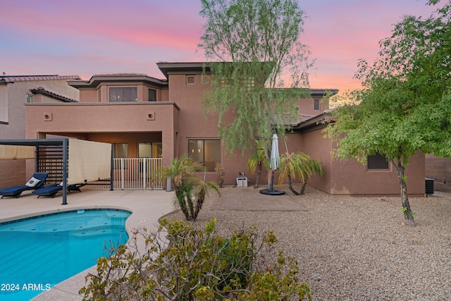 pool at dusk featuring a patio area and central air condition unit