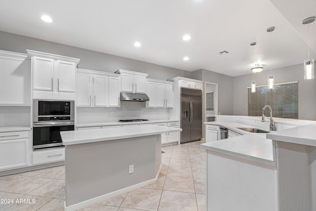 kitchen with built in appliances, an island with sink, hanging light fixtures, sink, and white cabinetry