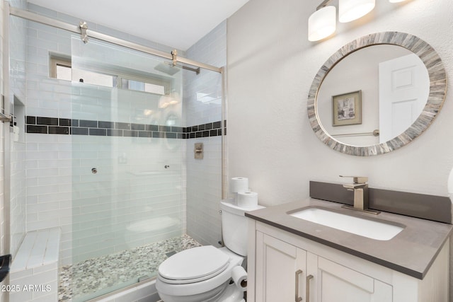 bathroom featuring toilet, vanity, and a shower with door