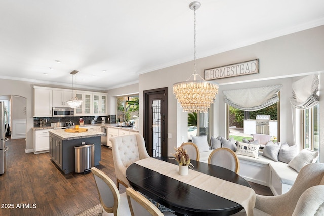 dining area with plenty of natural light, dark hardwood / wood-style floors, ornamental molding, and a chandelier