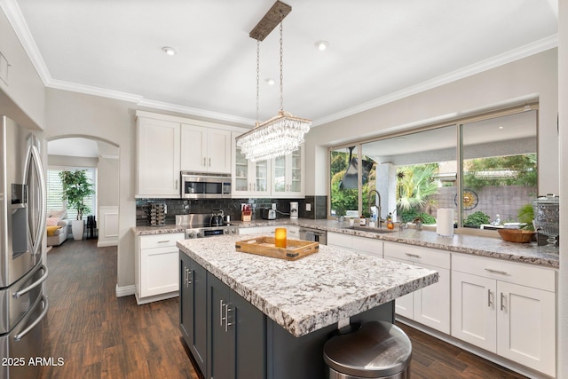 kitchen featuring sink, white cabinetry, stainless steel appliances, and hanging light fixtures