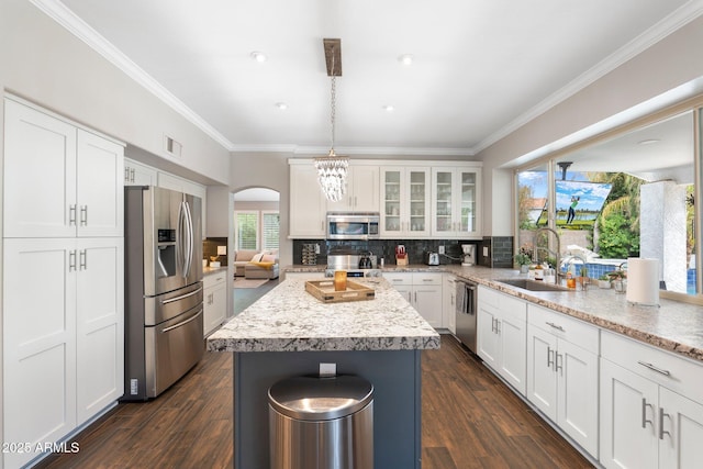 kitchen with pendant lighting, a kitchen island, sink, white cabinetry, and appliances with stainless steel finishes