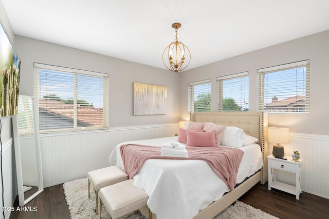 bedroom with an inviting chandelier, dark hardwood / wood-style floors, and multiple windows