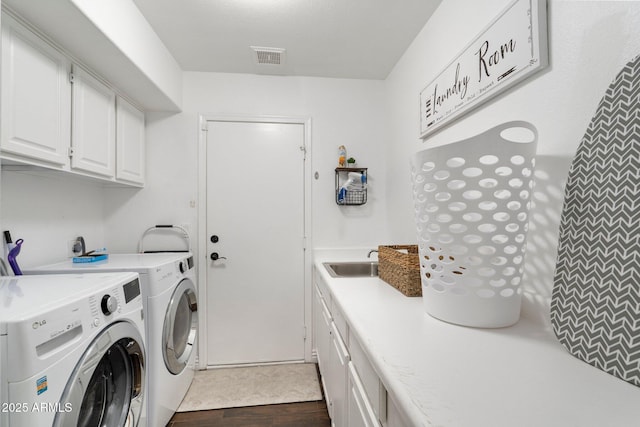 laundry area featuring dark hardwood / wood-style floors, cabinets, washing machine and clothes dryer, and sink