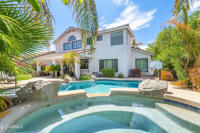 back of property featuring a pool with hot tub and a patio