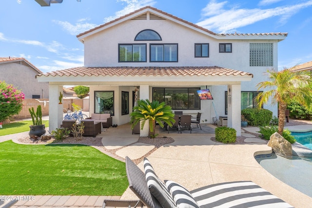 back of property with outdoor lounge area, a fenced in pool, a yard, and a patio